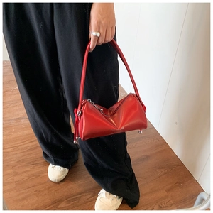 Macro detail of red smooth leather pillow bag with metallic ball feet and zip closure