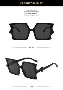 Close-up of black oversized rectangle sunglasses featuring gothic bat wing frame edges