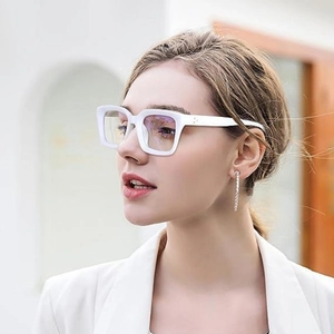 Detail view of bold white square frame glasses with rivet accents on a female model