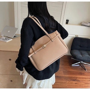 Detail of khaki shoulder tote bag with gold metal buckle on female model in casual outfit