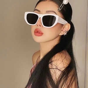 Close-up of white chunky sunglasses with dark lenses worn by a fashion model with pearls