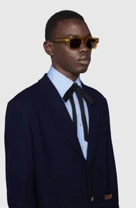 Side view of model wearing thick amber tortoiseshell rectangular sunglasses