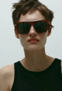 Close-up of stylish square amber sunglasses with thick frames and golden metal accents