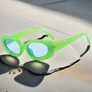 Détail de lunettes œil de chat vert néon avec verres bleus sur une surface en pierre