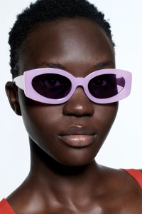 Close-up of lavender cat-eye sunglasses worn by a model with a clean white background
