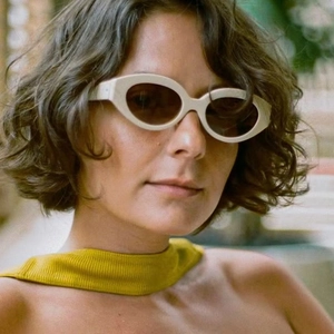 Detail shot of ivory vintage oval sunglasses with thick frames and brown tinted lenses