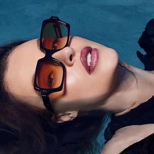 Modische quadratische schwarze Sonnenbrille mit orangen Gläsern in Pool-Szene präsentiert