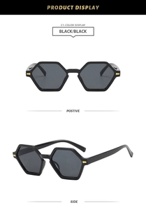 Detail view of black hexagonal sunglasses with golden metal hinges and dark grey lenses