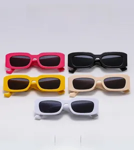 Flat lay of five chunky square frame sunglasses in pink, black, yellow, beige, and white