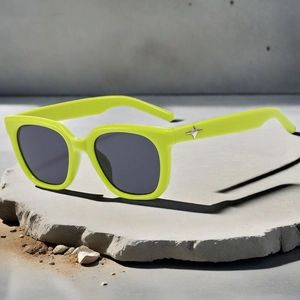 Detail of neon green square sunglasses with silver star decor on textured stone