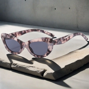 Detail of pink marble cat-eye sunglasses with dark grey lenses on concrete stone