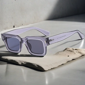 Detailed shot of transparent purple square sunglasses on a grey stone slab with soft shadows