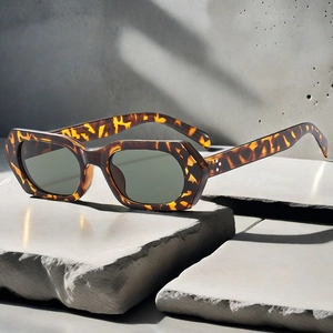 Detailed close-up of retro tortoiseshell sunglasses with silver rivet accents on stone