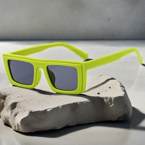 Detail of neon yellow square sunglasses on a grey stone texture with grey lenses