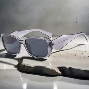 Detail shot of square gray-purple sunglasses with engraved temple arm on stone base