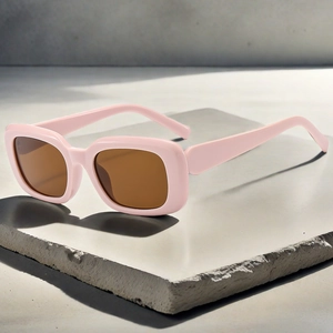 Detail of pink square frame sunglasses with tea lenses on a textured stone surface