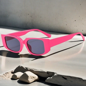 Vue détaillée de lunettes de soleil carrées rose néon rétro sur surface béton