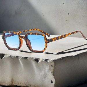 Gros plan de lunettes de soleil carrées écaille avec verres dégradés bleus sur pierre