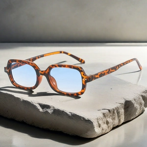 Détail macro de lunettes de soleil carrées en écaille avec verraille avec verres bleus sur fond de pierre