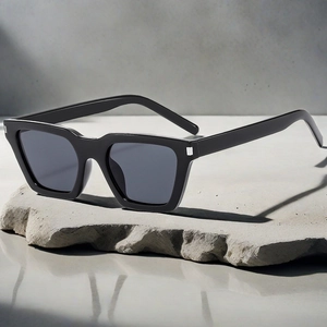 Detail of black square frame sunglasses with silver metal accents on a grey stone base