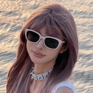 Close-up of white chunky cat-eye sunglasses on model with lavender hair and spiked choker