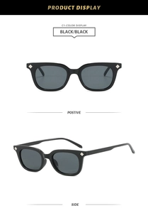 Close-up of black square sunglasses with silver diamond rivets and deep black lenses