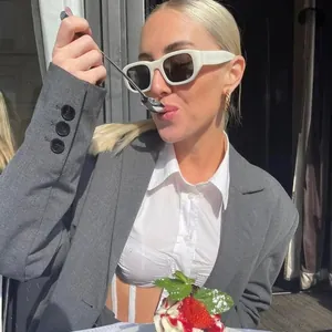 Occhiali da sole squadrati bianchi con montatura spessa indossati da una modella