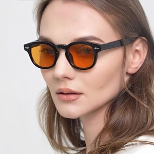 Close-up of trendy black chunky oval sunglasses with orange lenses on a model