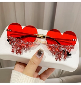 Detail of red heart-shaped sunglasses featuring cascading white rhinestone teardrops