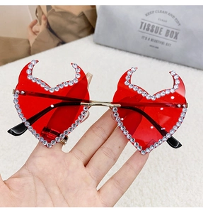 Detail of red heart-shaped devil sunglasses with sparkling rhinestones and gold metal arms