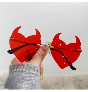 Detail of red heart-shaped devil sunglasses with gold nose bridge and small horns