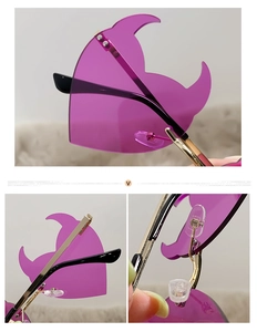 Detail view of heart-shaped devil sunglasses with purple lenses and gold metal temples