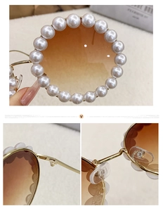 Detail of round sunglasses with pearl-studded frame and golden wavy metal temples