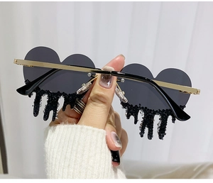 Close-up of heart-shaped sunglasses featuring dripping crystal fringe and golden metal frame