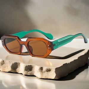 Detail view of stylish geometric sunglasses on stone showing the green transparent temples
