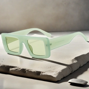 Detail of light green jelly square frame sunglasses with wide temples on a stone slab