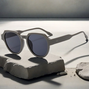 Gros plan de lunettes de soleil géométriques taupe posées sur une pierre grise
