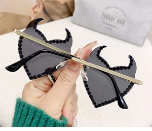Close-up of black devil wing sunglasses with diamond rivets and gold metal temples