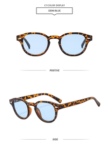 Detail view of oval tortoise shell sunglasses with blue lenses and metal rivet accents