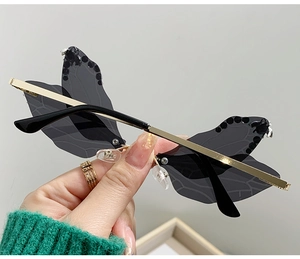 Detail of rimless dragonfly wing sunglasses with grey lenses and gold metal temples