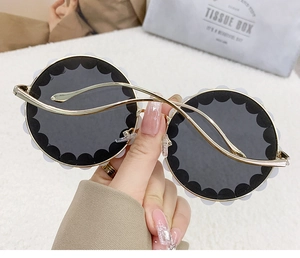 Detail of round sunglasses featuring white wavy trim and gold metal temple design