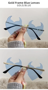 Detail view of rimless heart sunglasses with blue lenses and gold devil horn accents