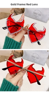Detail of red heart sunglasses with devil horns, gold frame, and rhinestone trim