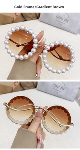 Detail of luxury round pearl sunglasses with gold wavy metal temples and brown gradient lenses