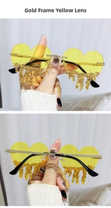 Detail of heart-shaped sunglasses with gold frame, yellow lenses, and tear-drop crystals