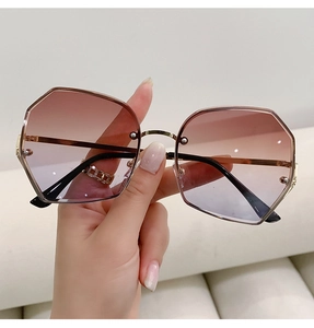 Close-up of geometric octagonal sunglasses with red-purple gradient lenses and gold frame