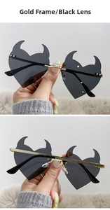 Detail of heart-shaped devil horn sunglasses with gold metal frame and black lenses