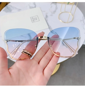Detailed shot of rimless square sunglasses with blue-pink gradient lenses and gold frames