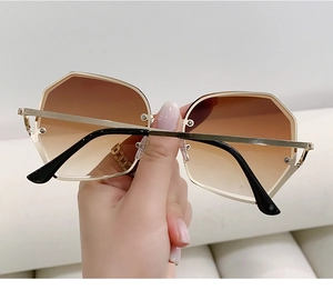 Detail of trendy polygonal sunglasses with gradient lenses and gold metal frames