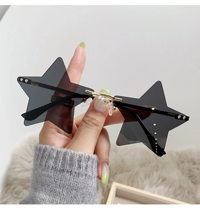 Close-up of star-shaped rimless sunglasses with grey lenses and gold metal temples